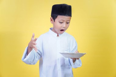 Asyalı bir çocuk elindeki levhaya şaşırmış görünüyor. Ramdan Kareem kutlaması..