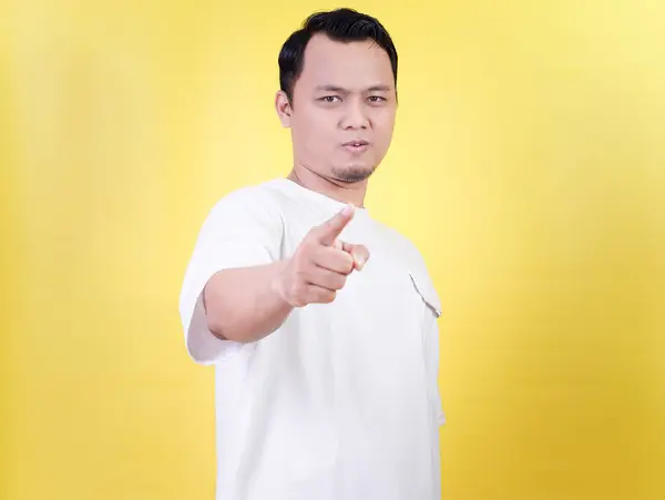 Asyalı bir adam kendinden emin bir şekilde parlak sarı bir arkaplanı işaret ediyor..