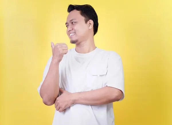 Gülümseyen Asyalı bir adam, parlak sarı bir arka plana karşı sırtına doğru baş parmak işareti yapıyor.