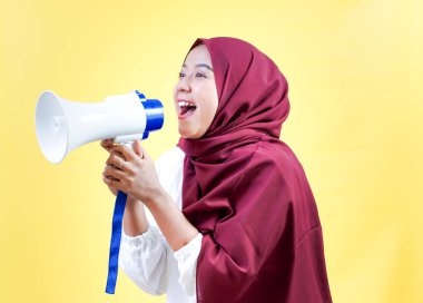 Neşeli Asyalı, tesettürlü Müslüman bir kadın heyecanla megafona konuşuyor..