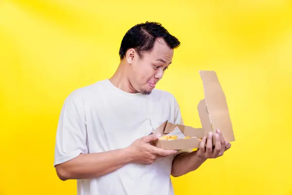 Beyaz gömlekli bir adam ilginç bir şekilde yemek siparişini canlı sarı bir arka planla karşılaştırıyor. Uluslararası Gıda Günü konsepti