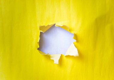Yırtık sarı kağıt beyaz bir arkaplan ortaya çıkarır, parlak ve nötr renkler arasında bir kontrastlık yaratır