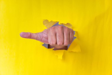Yırtık sarı bir kağıdı işaret eden bir el, yönü, komutu ya da suçlamayı simgeliyor..