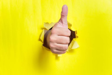 Pozitifliği sembolize eden, sarı arkaplandan onay veren bir el.