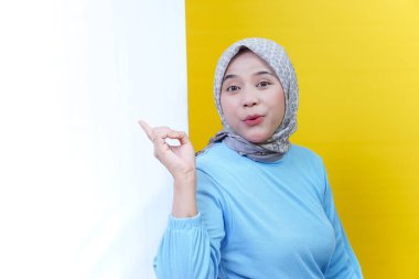 Tesettürlü ve mavi elbiseli neşeli bir Asyalı kadın kendini ifade ederek eğlenceli ve çekici bir atmosfer yaratıyor..