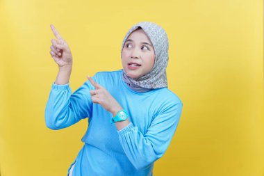 Tesettürlü ve mavi gömlekli Asyalı bir kadın merakını ve heyecanını dışa vuruyor..