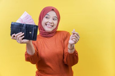 Bir Asyalı Müslüman kadın para dolu bir cüzdan tutuyor, sanki para teklif ediyor ya da istiyor gibi el hareketi yapıyor..