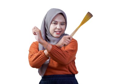 Tesettürlü Asyalı bir kadın elinde ahşap bir spatula tutarken X hareketi yapıyor. Beyaz arka planda izole edilmiş bir uyarı ifadesi gösteriyor.