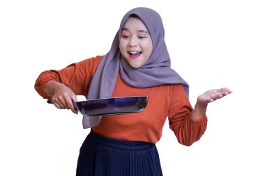 Tesettürlü Asyalı bir kadın kızartma tavasını zevkle tutar, yemek yaparken heyecanını ifade eder. beyaz arkaplanda izole.