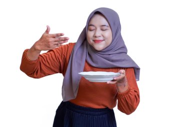 Tesettürlü neşeli bir Asyalı kadın zevkle ve takdiriyle yemeğin tadını çıkarıyor. beyaz arkaplanda izole.