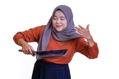 Tesettürlü Asyalı bir kadın yemek yaparken yemek pişirmekten zevk alır. Mutfak tutkusunu somutlaştırır. beyaz arkaplanda izole.