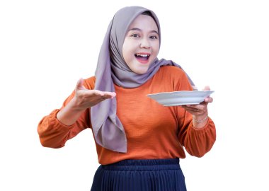 Boş bir tabak sunan tesettürlü Asyalı kadın, neşeli bir jestle yemek ya da yemek öneriyor..