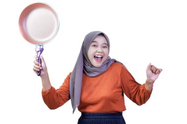 Tesettürlü mutlu Asyalı genç kadın kızartma tavasını tutuyor ve el sallıyor, neşeli yemeklere hazır..