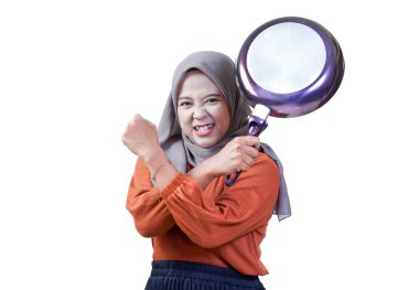 Kafiyeli kararlı Asyalı kadın tavayla güç gösteriyor, güç ve güven ifade ediyor..