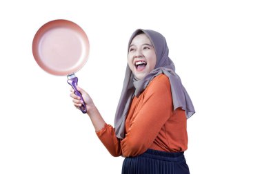 Tesettürlü mutlu Asyalı genç kadın kızartma tavasını tutuyor ve el sallıyor, neşeli yemeklere hazır..
