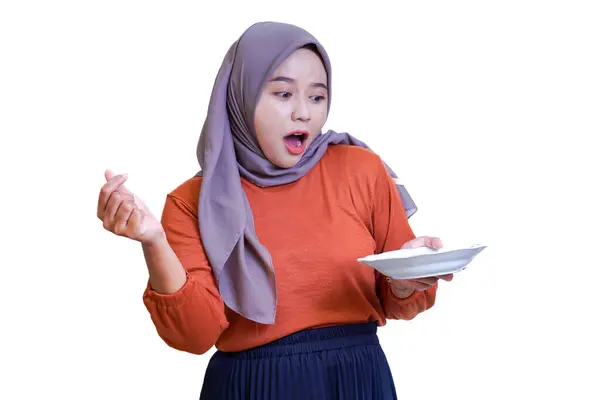 Tesettürlü şaşırmış Asyalı kadın, bir tabak tutarken, sevgi ve sıcaklığı göstererek parmak kalp hareketi yapıyor..