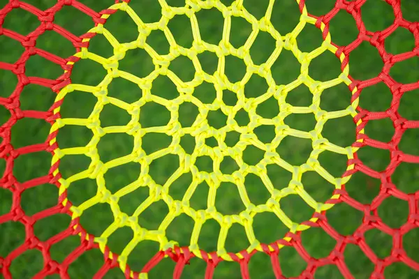Dairesel geometrik desen oluşturan sarı ve kırmızı iplerle örülmüş renkli bir ağın yakın çekimi.