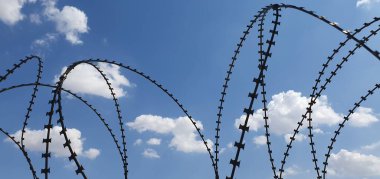 Barbed wire in the background of the sky. Concepts of detention, border closure, prison or loss of freedom. clipart