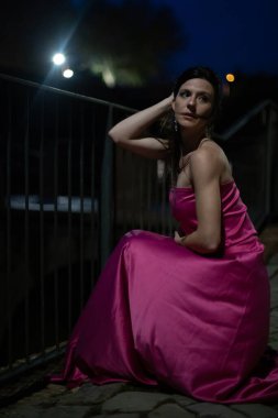 Renkli ve zarif tasarımcı elbiseli bir kadın gece bir şatonun önünde poz veriyor..