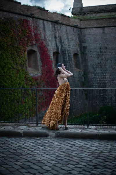 İspanyol kalesinin önünde poz veren zarif bir elbise giymiş bir kadın..