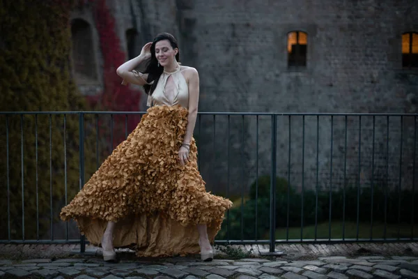 İspanyol kalesinin önünde poz veren zarif bir elbise giymiş bir kadın..