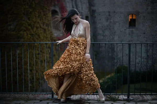 İspanyol kalesinin önünde poz veren zarif bir elbise giymiş bir kadın..