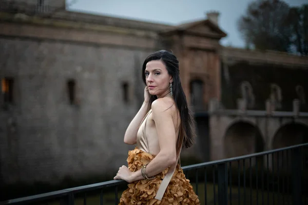 İspanyol kalesinin önünde poz veren zarif bir elbise giymiş bir kadın..