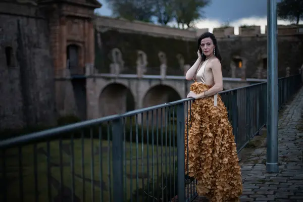 İspanyol kalesinin önünde poz veren zarif bir elbise giymiş bir kadın..