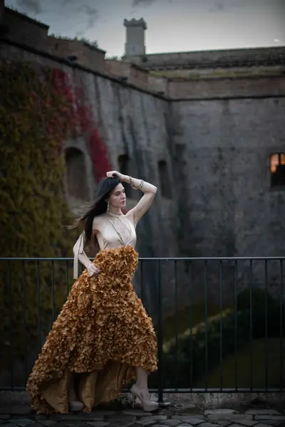 İspanyol kalesinin önünde poz veren zarif bir elbise giymiş bir kadın..