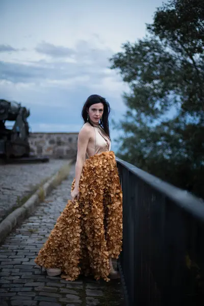 İspanyol kalesinin önünde poz veren zarif bir elbise giymiş bir kadın..