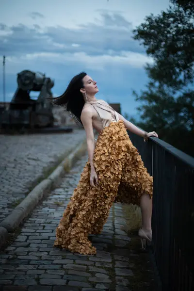 İspanyol kalesinin önünde poz veren zarif bir elbise giymiş bir kadın..