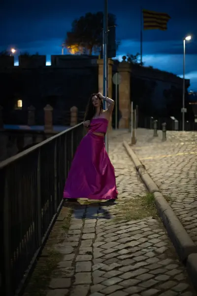 Renkli ve zarif tasarımcı elbiseli bir kadın gece bir şatonun önünde poz veriyor..