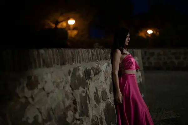 Renkli ve zarif tasarımcı elbiseli bir kadın gece bir şatonun önünde poz veriyor..