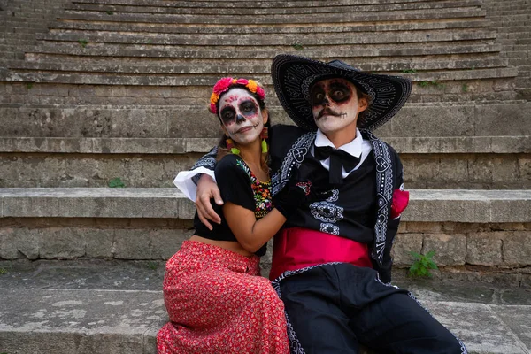 Catrine gibi giyinmiş, birbirine sarılmış iki genç.