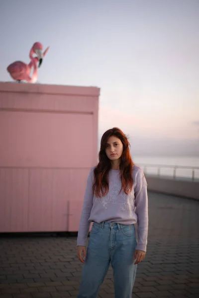 Pembe arka plandaki genç kadın gün doğumunda okyanusun önünde