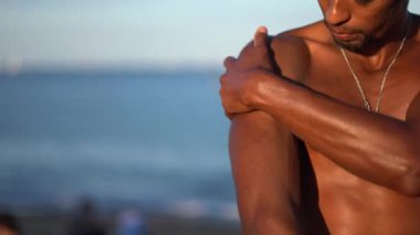 Genç çok ırklı model plajda güneş kremi sürüyor, deniz görülebilir.