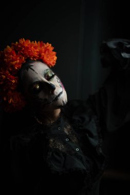 Geleneksel bir Catrina 'nın çarpıcı yüksek kontrastlı portresi gözleri kapalı, huzur hissi veriyor. Dekorasyonlarının parlak renkleri koyu siyah arka plana karşı çarpıcı ve büyüleyici bir görüntü oluşturuyor..