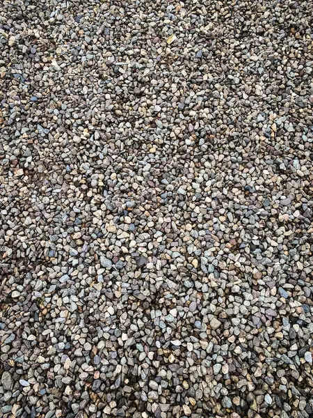 Pek çok küçük gri taşın yakın çekim görüntüsü. Çakıl taşları sıkıca paketlenmiştir. Bu da tek tip ve doğal bir doku yaratır..