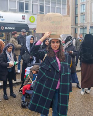 A woman join Pro Palestine Protest, 16 December 2023 , in Southampton, United Kingdom. She stands confidently in the foreground, holding up a hand-drawn protest sign that reads 