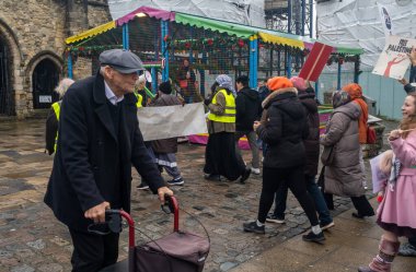 People take part in pro-Palestine protests, 16 december 2023, Southampton, UK. In the background, a group of people  engaged in Pro-Palestine protest with signs and colorful attire.