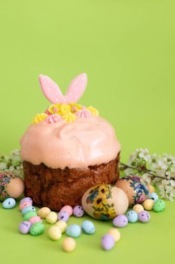 Geleneksel Paskalya pastası pembe jöleli ve yeşil üzerine boyanmış yumurta ve şeker şekerlemeleriyle çevrili tavşan kulaklı..