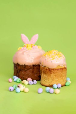 Yatay çerçeve, etrafa saçılmış yumurta şekerli iki Paskalya pastası gösteriyor, neşeli ve neşeli bir Paskalya havası yaratıyor..