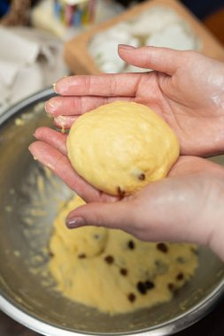 Dişi eller, geleneksel Paskalya ekmeği pişirmeye hazır zengin sarı hamur topunu dikkatlice şekillendiriyor..