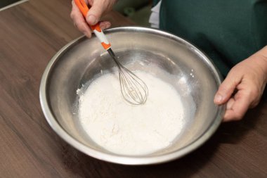 Metal bir kasede çırpılmış un ve süt, ev yapımı hamur yapma sürecinin başlangıcını yakalıyor..