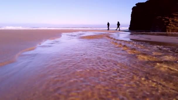 很好的电影视频剪辑 展示了里巴多奥的大教堂海滩 一对夫妇沿着海滩散步 在加利西亚拍摄这个美丽的旅游胜地 — 图库视频影像
