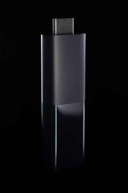 Siyah yansıtıcı yüzeyde çekilmiş USB-C akış çubuğunun sanatsal görüntüsü. Temiz ve modern kompozisyon teknolojiyle ilgili içerik, dijital yenilik, akıllı ev ve medya için kullanışlı