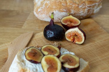 Tahtada taze incir, yumuşak peynirli bir dilim ekmek ve incir..