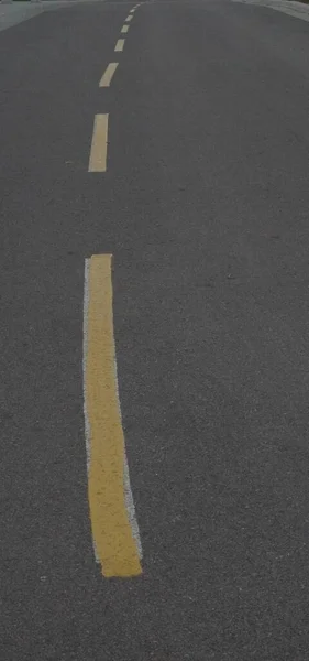 Close up of a road with a curvature and yellow dividing lane lines