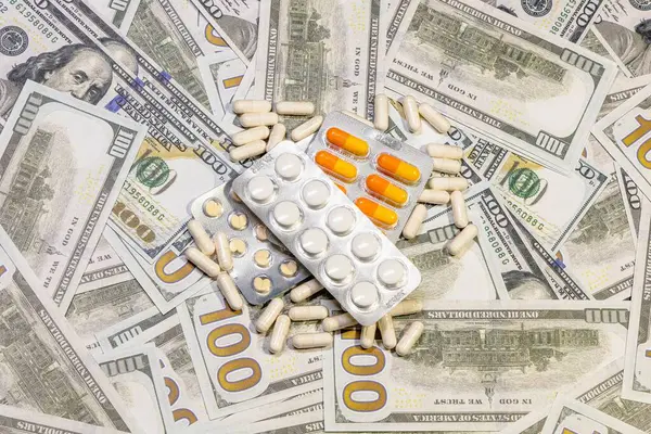 American currency banknote with medical drugs and dietary supplements in the form of tablets as a link to corruption in pharmaceuticals.