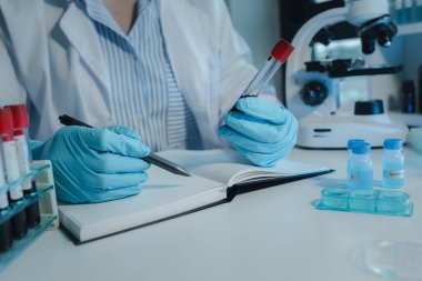 Kimyager kandaki kimyasalları araştırmak için mikroskop kullanıyor. Bilim adamı laboratuvarda kimyasallarla deney yapıyor. Kimyager test tüplerindeki kimyasalları kimyasal reaktörlerle ayırıyor.,